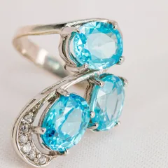 A blue topaz ring in white gold, three oval gems set in a curve
