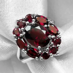 A deep red garnet cluster ring resting on white silk