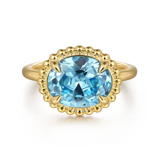An oval blue topaz ring in a beaded 14K yellow gold frame, by Gabriel & Co.