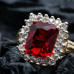 A ruby ring in a halo of diamonds on black silk