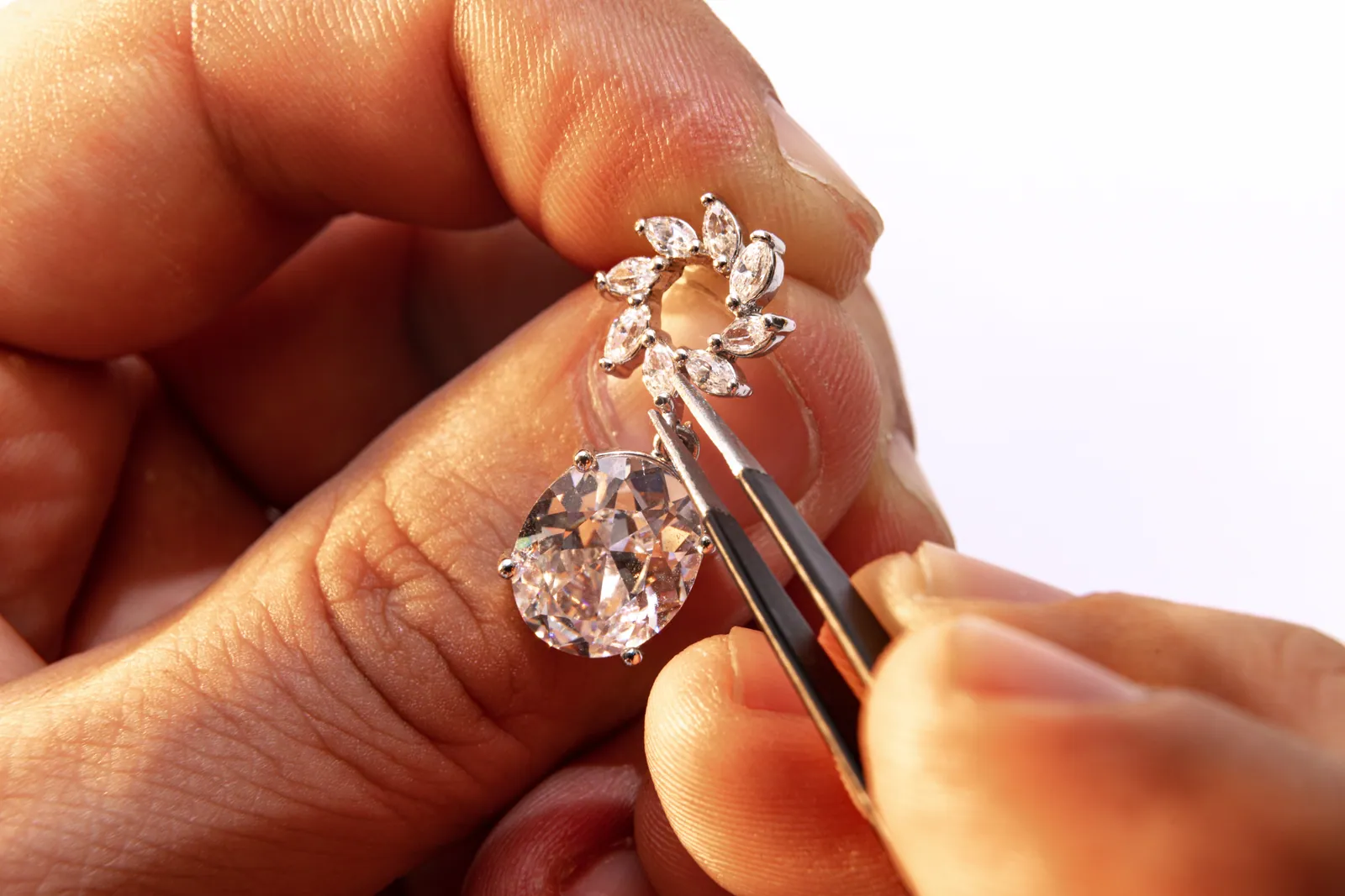 A diamond held in tweezers above its setting