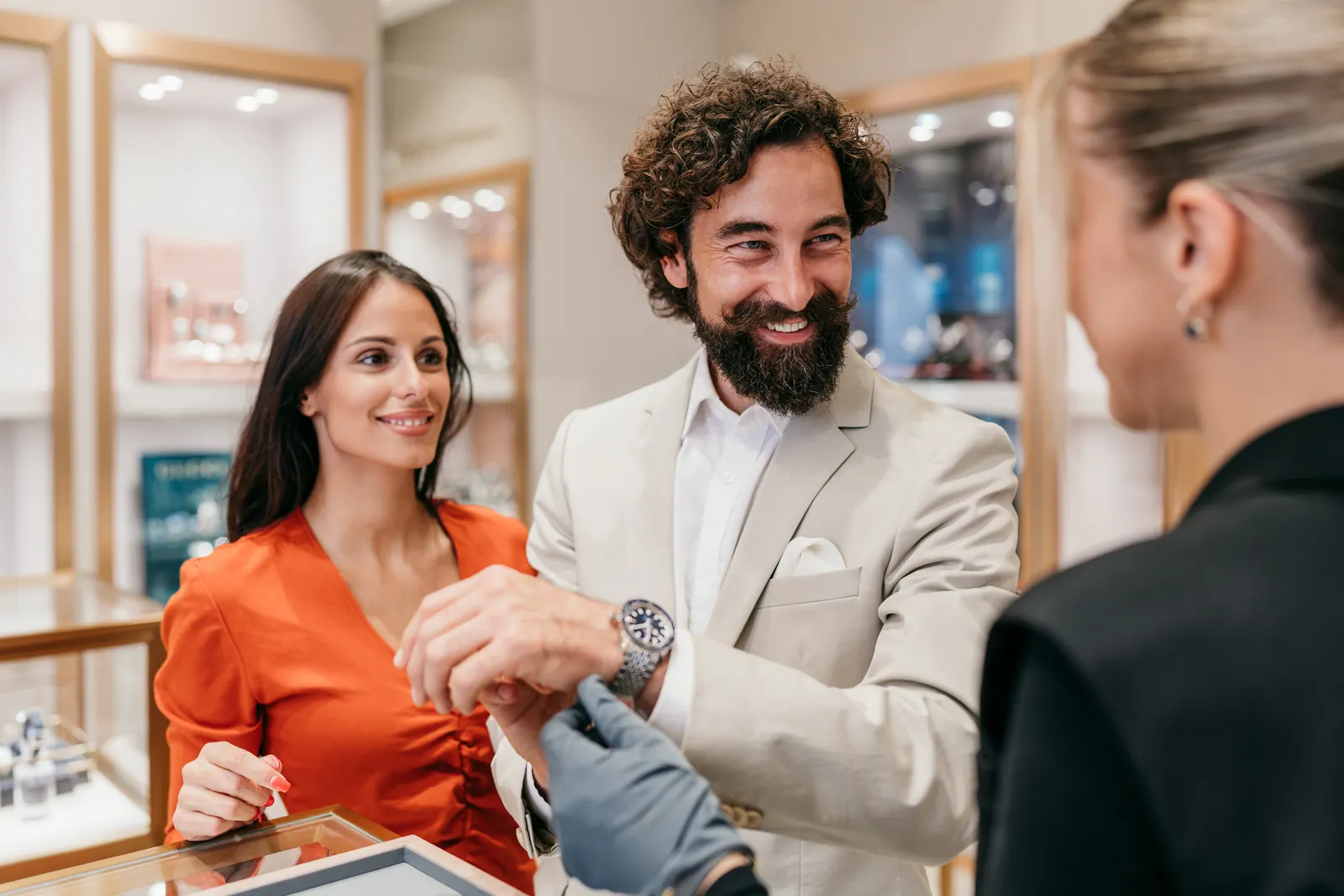 A guest trying a steel watch at the showroom case while a gloved hand fastens the bracelet
